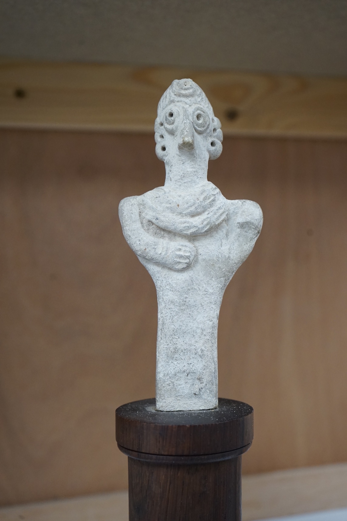 A Syro-Hittite pottery figure, on columnar rosewood stand, 29cm high
